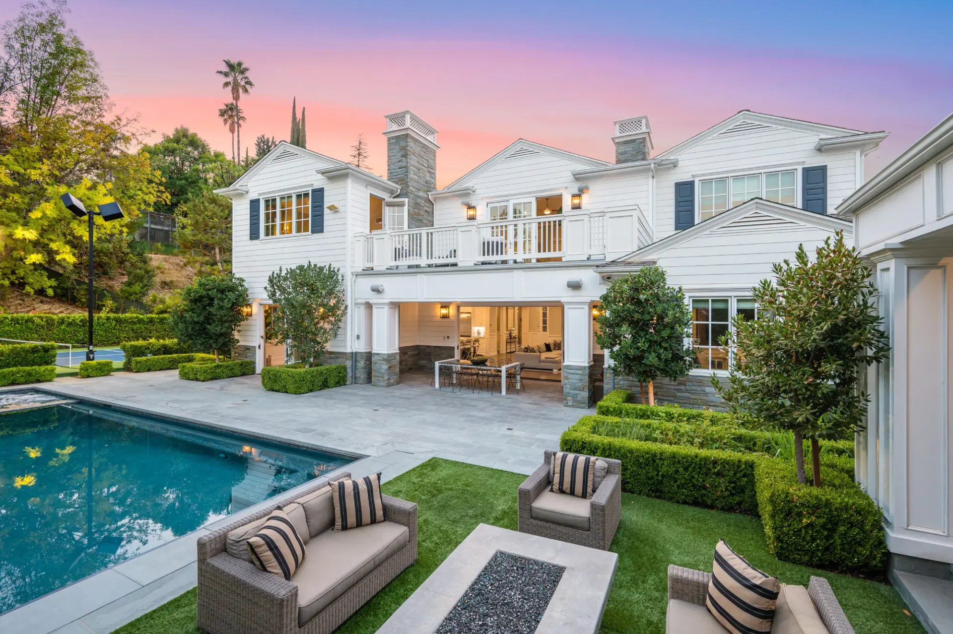 A large white house with a pool and lawn.